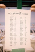 Load image into Gallery viewer, Wedding seating chart displayed at a real reception with guest names and table numbers